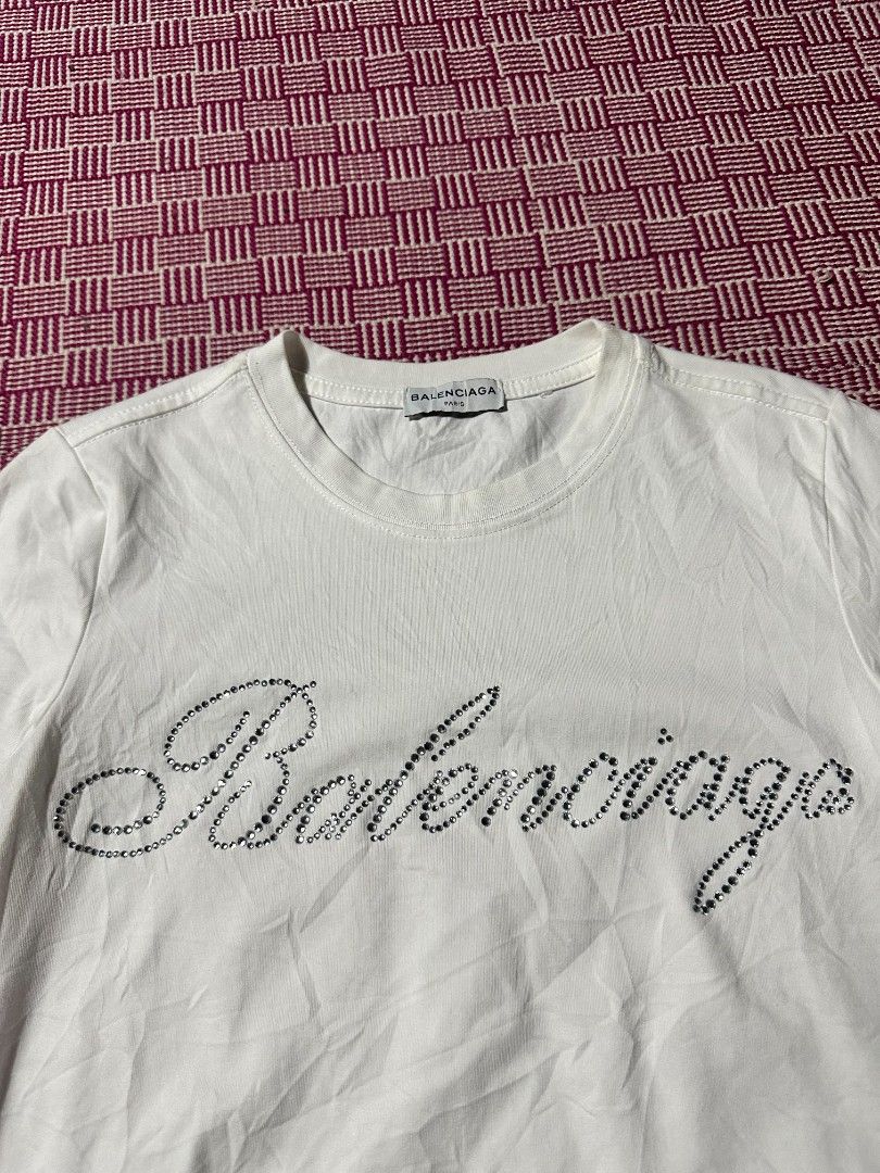 Balenciaga White Rhinestone Script Logo T-Shirt Size M (Category: Shirts) located in Manila. Submitted by wardrobeph.com (Listing ID 1470124683, Image 3). Description: - Authentic Balenciaga white t-shirt - Eye-catching rhinestone brand logo across the chest - Size: M (tag inside collar) - Classic crew neck and short sleeves - Clean overall condition with minor wrinkles from storage - Long care label attached at inner side seam.