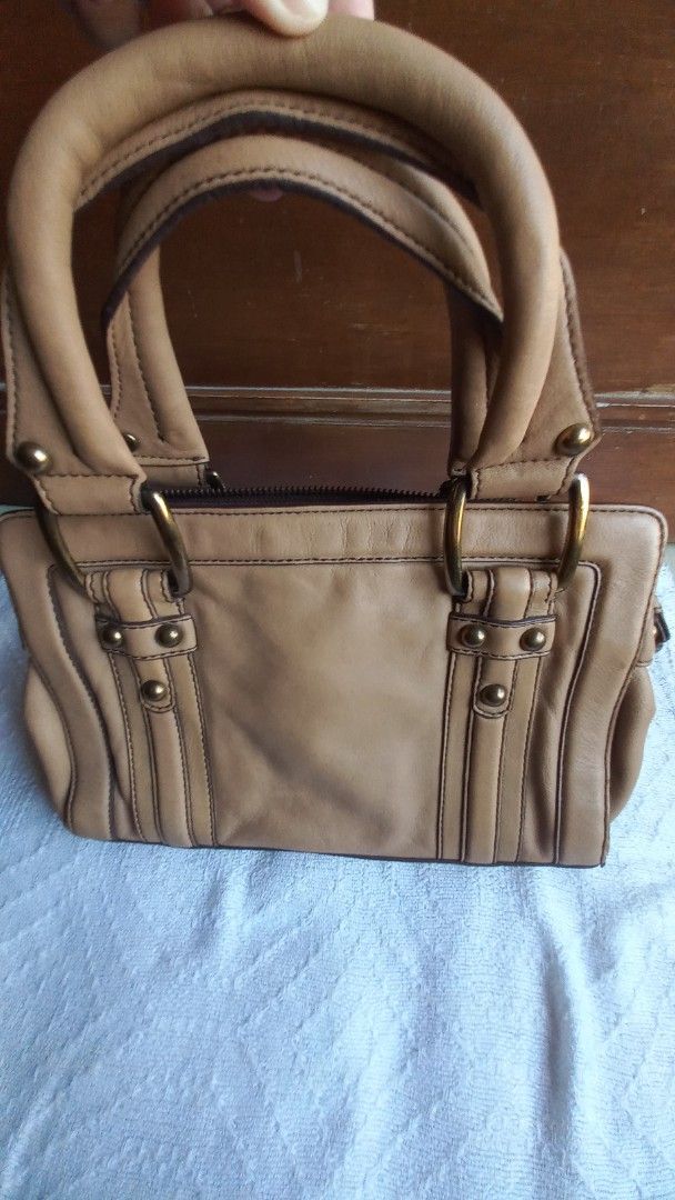 Banana Republic Tan Leather Handbag (Category: Luxury Bags & Wallets) located in Rizal. Submitted by mayra74 (Listing ID 1470141380, Image 2). Description: - Brand: Banana Republic - Material: Genuine cow leather shell with brown fabric lining - Color: Tan with brass-tone hardware - Closure: Zipper top closure - Handles: Dual carrying handles - Interior: Clean with a zippered pocket and brand logo plaque - Condition: Clean interior and exterior.