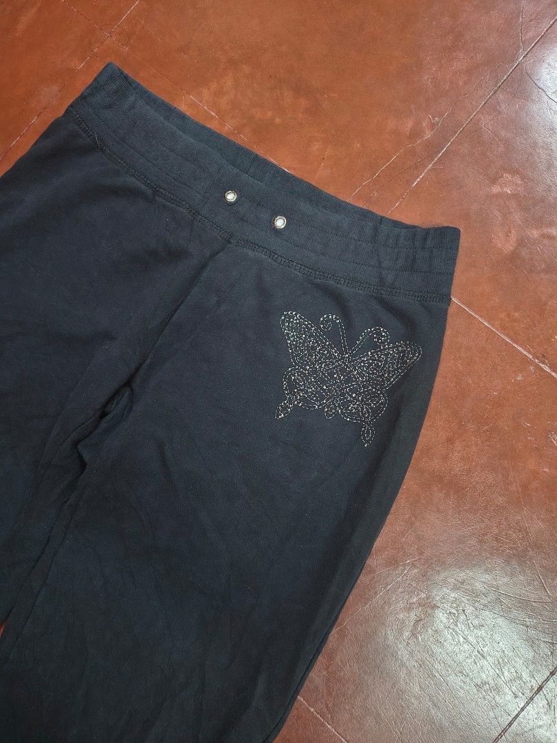 BCBGMAXAZRIA Black Rhinestone Embellished Sweatpants (Category: Jeans) located in Bani. Submitted by ger.0 (Listing ID 1470085796, Image 3). Description: - Brand: BCBGMAXAZRIA - Color: Black - Design: Rhinestone butterfly graphic on the hip and rhinestone lettering down the leg - Waistband: Elastic with drawstring grommets - Material: Soft, high-quality cotton - Fit: Easy pull-on style, super comfortable for lounging or casual wear.