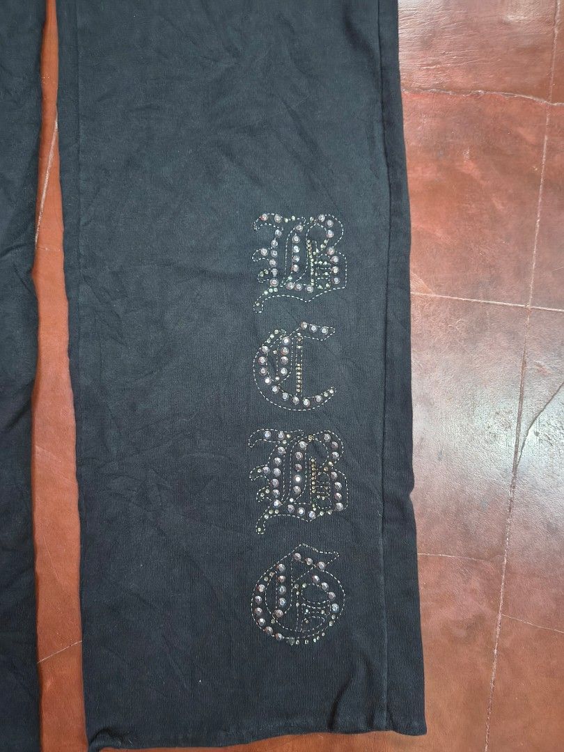 BCBGMAXAZRIA Black Rhinestone Embellished Sweatpants (Category: Jeans) located in Bani. Submitted by ger.0 (Listing ID 1470085796, Image 2). Description: - Brand: BCBGMAXAZRIA - Color: Black - Design: Rhinestone butterfly graphic on the hip and rhinestone lettering down the leg - Waistband: Elastic with drawstring grommets - Material: Soft, high-quality cotton - Fit: Easy pull-on style, super comfortable for lounging or casual wear.