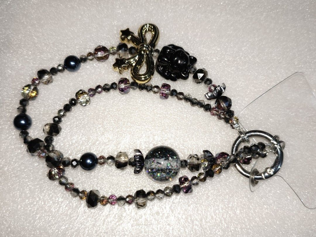 Beaded Phone Strap Wrist Lanyard Charm Strap (Category: Charms) located in Caloocan City. Submitted by books_and_beads (Listing ID 1470081213, Image 3). Description: - Handmade double-strand beaded phone wrist strap - Features sleek black beads, dark crystals, and a sparkly glitter sphere - Adorned with a cute gold bow charm: · Left Chain: A dramatic, mystical, and glamorous design. The centerpiece is a striking black nine-tailed fox charm paired
