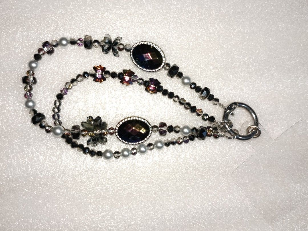 Beaded Phone Strap Wrist Lanyard Charm Strap (Category: Charms) located in Caloocan City. Submitted by books_and_beads (Listing ID 1470081213, Image 2). Description: - Handmade double-strand beaded phone wrist strap - Features sleek black beads, dark crystals, and a sparkly glitter sphere - Adorned with a cute gold bow charm: · Left Chain: A dramatic, mystical, and glamorous design. The centerpiece is a striking black nine-tailed fox charm paired