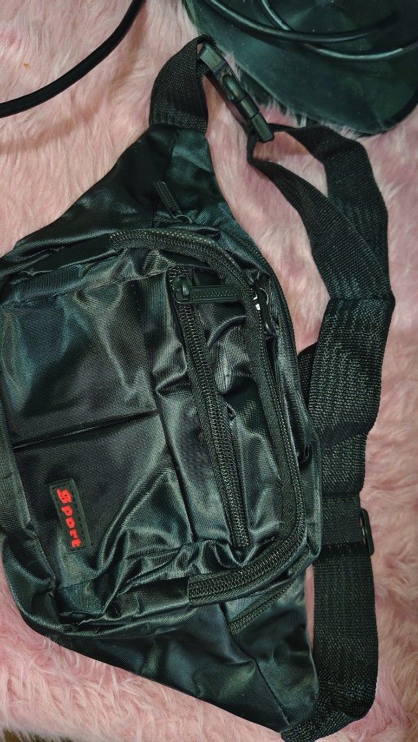 Belt bag black (Category: Belt bags, Clutches and Pouches) located in Pasay City. Submitted by taytayswifty (Listing ID 1469985926, Image 2). Description: - Color: Black - Material: Durable nylon - Compartments: Multiple zipped pockets for easy organization - Accent: Distinctive red Sport label on the front pocket - Strap: Adjustable with a secure plastic buckle closure - Best for: Running errands, working out, or casual daily use.