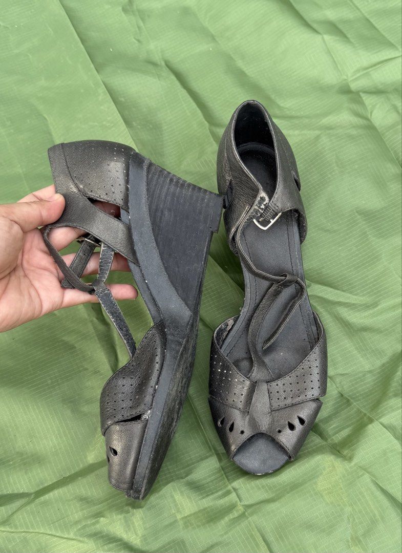 Black metallic peep-toe wedge sandals with T-strap design (Category: Wedges) located in Cavite. Submitted by maxs.bl (Listing ID 1469956484, Image 2). Description: - Color/Finish: Metallic black - Style: Peep-toe wedge sandals with T-strap and ankle buckle closure - Details: Perforated cut-outs and teardrop accents on upper straps - Heel: Substantial wedge for added height and stability - Condition: Pre-owned with light scuffing and wear on the i