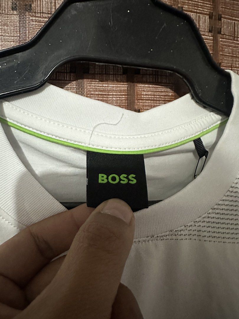 BOSS White Geometric Pattern T-Shirt Size M (Category: Tshirts & Polo Shirts ) located in Manila. Submitted by thrift.zone1 (Listing ID 1470093270, Image 2). Description: - Brand: BOSS - Color: White with neon green inner collar piping - Size: M - Material: 95% Cotton, 5% Spandex (comfortable stretch fit) - Design: Bold geometric graphic print across the front and sleeves with subtle embroidered BOSS logo on the chest - Condition: Excellent, care