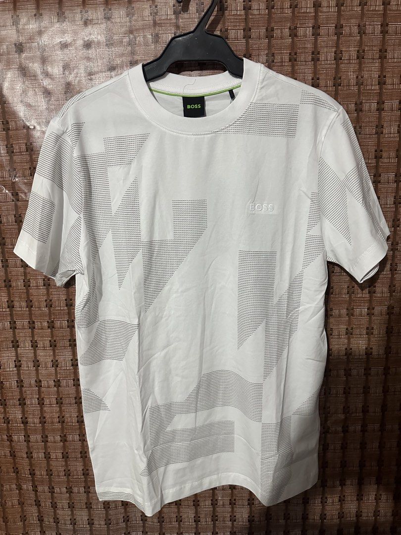 BOSS White Geometric Pattern T-Shirt Size M (Category: Tshirts & Polo Shirts ) located in Manila. Submitted by thrift.zone1 (Listing ID 1470093270, Image 1). Description: - Brand: BOSS - Color: White with neon green inner collar piping - Size: M - Material: 95% Cotton, 5% Spandex (comfortable stretch fit) - Design: Bold geometric graphic print across the front and sleeves with subtle embroidered BOSS logo on the chest - Condition: Excellent, care
