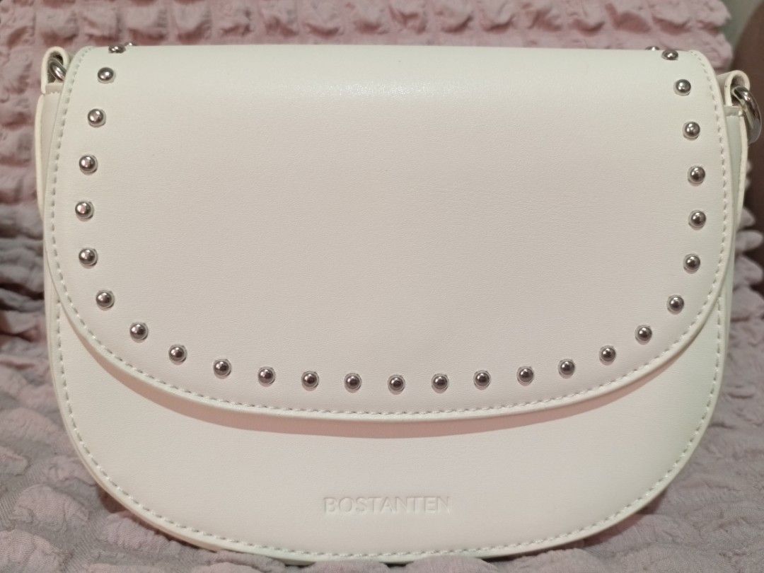 Bostanten White Studded Crossbody Bag (Category: Cross-body Bags) located in Caloocan City. Submitted by micheshop_1 (Listing ID 1470092574, Image 1). Description: - Brand: Bostanten crossbody bag - Color: White - Closure: Studded flap with magnetic snap - Strap: Adjustable and still wrapped in plastic - Interior: Fabric-lined with card slots and a zipper pocket - Condition: Brand new with tags attached, exceptionally clean inside and out.