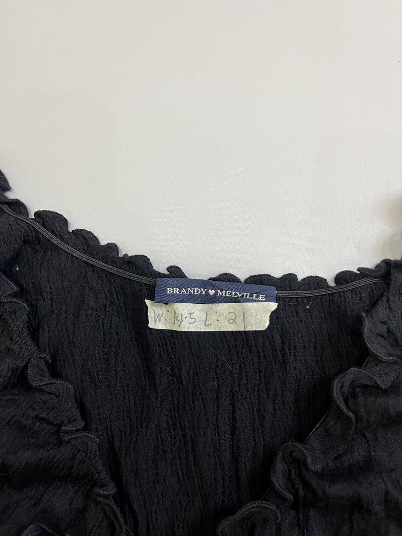 Brandy Melville Black Ruffle Bow Tank Top (Category: Sleeveless) located in Mabalacat. Submitted by aas_thriftfings (Listing ID 1470105655, Image 3). Description: - Brand: Brandy Melville - Color: Black - Material: 55% cotton, 42% polyamide, 3% spandex (lightweight & stretchable) - Design: Crinkled texture with V-neckline, delicate ruffles, and capped sleeves - Detail: Cute center-front satin bow accent - Care: Machine washable - Condition: Brand