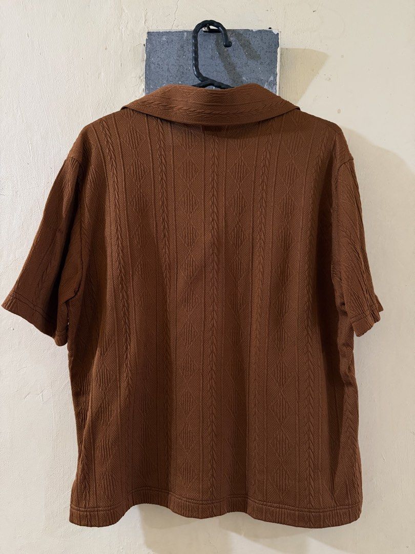 Brown Polo Shirt (Category: Tshirts & Polo Shirts ) located in Las Pinas. Submitted by rareriroruru (Listing ID 1470053172, Image 2). Description: - Color: Rich brown - Size: Medium - Length: 22 in - Width: 20 in - Style: Relaxed fit knit polo shirt with short sleeves - Neckline: Open V-neck collar design - Details: All-over textured pattern on front and back - Material: Comfortable fabric with great stretch.