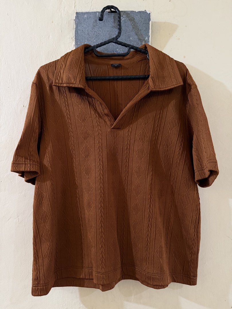 Brown Polo Shirt (Category: Tshirts & Polo Shirts ) located in Las Pinas. Submitted by rareriroruru (Listing ID 1470053172, Image 1). Description: - Color: Rich brown - Size: Medium - Length: 22 in - Width: 20 in - Style: Relaxed fit knit polo shirt with short sleeves - Neckline: Open V-neck collar design - Details: All-over textured pattern on front and back - Material: Comfortable fabric with great stretch.
