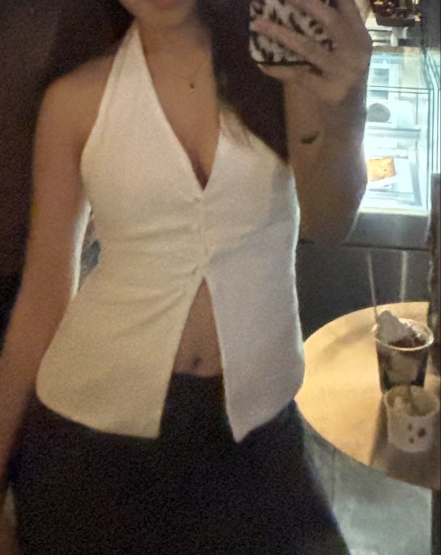 BSCO ARIA Halter Button Down Backless Top (Category: Sleeveless) located in Manila. Submitted by chicbyj (Listing ID 1469982538, Image 1). Description: - Color: White - Style: Halter top with deep V-neck and front buttons - Fit: Sleeveless, fitted silhouette - Detail: Waist-down split hem - Versatility: Pairs easily with dark bottoms - Occasion: Great for warm days or going out.