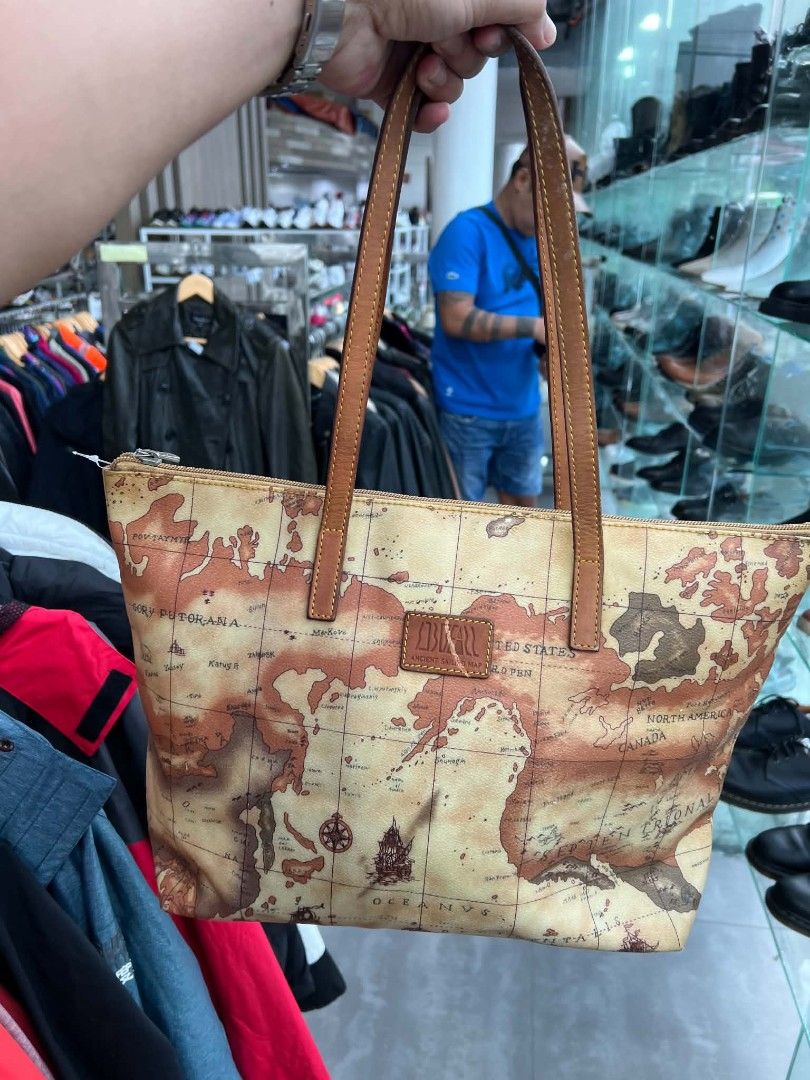 Bufall Vintage Map Print Tote Bag (Category: Tote Bags) located in Urdaneta. Submitted by jayceegarage (Listing ID 1470096007, Image 2). Description: Tan tote bag covered in an old-world map graphic. Brown leather shoulder straps and matching trim. Top zip closure keeps stuff secure. Inside lining is brown fabric with a zipper pocket. Structured bottom panel. Zipper pull has the Bufall logo stamped on it. Clean interior stuffed with plastic bags 