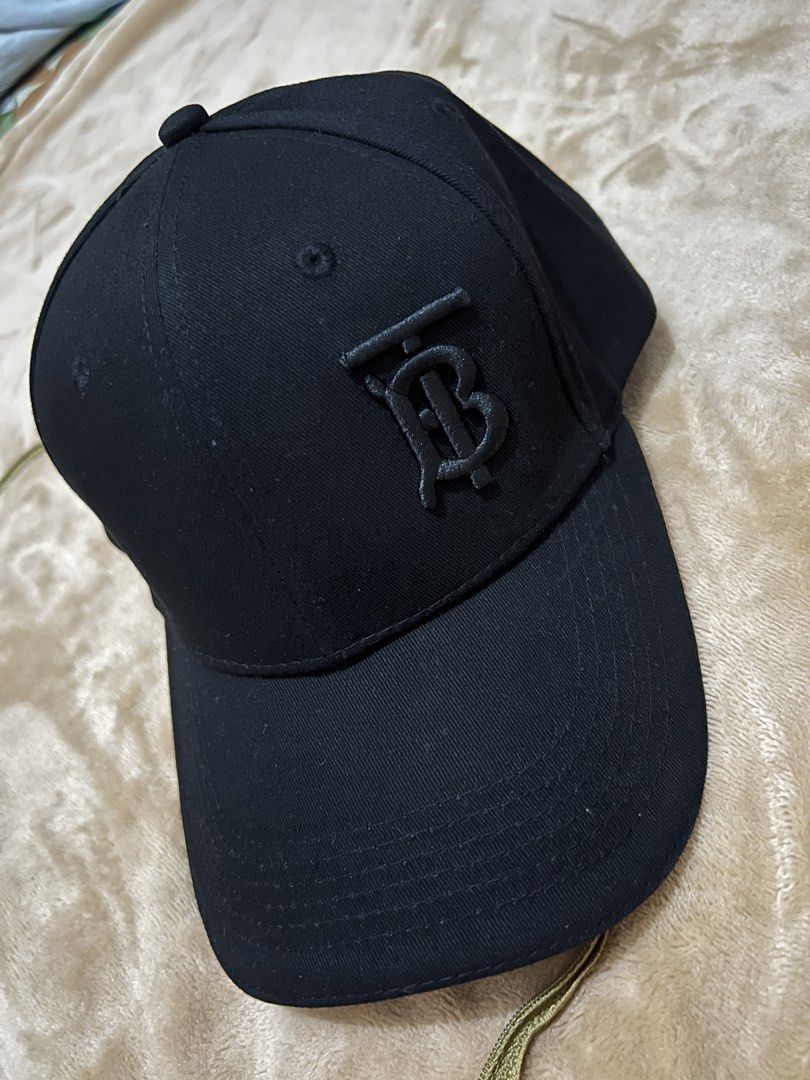 Burberry Black TB Monogram Baseball Cap (Category: Caps & Hats) located in Binan City. Submitted by thetidyqueen (Listing ID 1470076472, Image 1). Description: - Brand: Burberry - Color: Black with raised tonal TB monogram on the front - Brim: Underside features the classic vintage check pattern - Details: Branded interior strap tape and official London England tag - Fit: Adjustable strap at the back for a custom fit - Condition: Excellent, 100% 