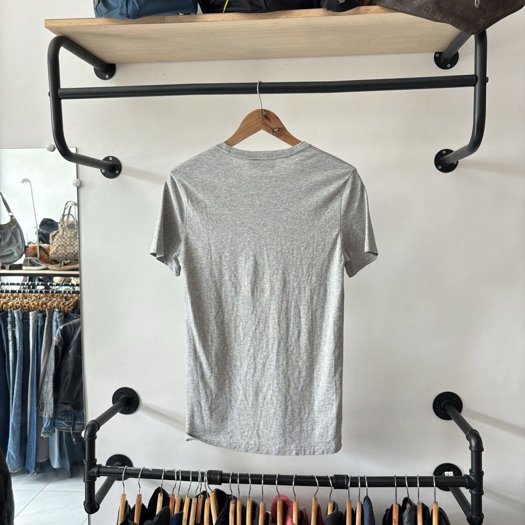 Burberry Grey T-Shirt Size M (Category: Shirts) located in Bambang. Submitted by heats777 (Listing ID 1470019100, Image 3). Description: - Brand: Burberry London England - Item: Grey short-sleeve t-shirt with crew neckline - Detail: Small red embroidered equestrian knight logo on left chest - Size: Tagged Medium (M) - Material: 100% Cotton, Made in China - Condition: Clean piece with minimal signs of wear - Style: Solid luxury basic for daily rot