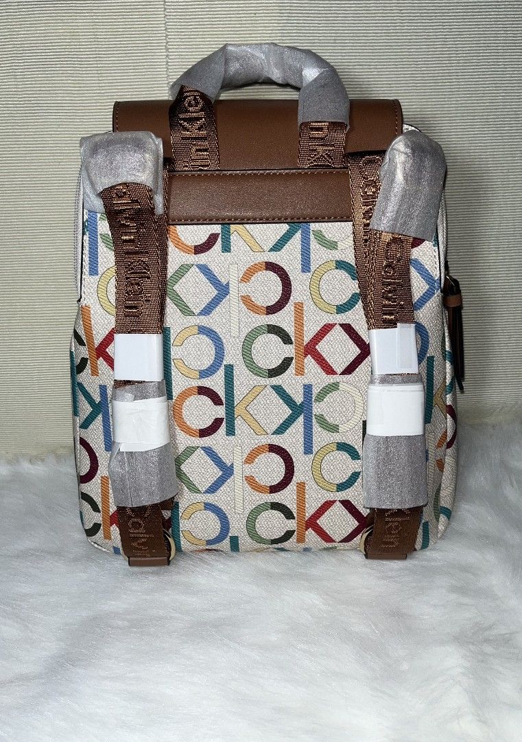Calvin Klein Mono Multi Color Women's Backpack (Category: Backpacks) located in Imus. Submitted by maria_pilayo (Listing ID 1469970384, Image 2). Description: - Brand: Calvin Klein - 💯% Authentic - Condition: Brand new, unused, still wrapped in protective factory packaging - Design: Mono multi-color print with brown top flap and straps - Branding: Calvin Klein metallic lettering on the front - Features: Adjustable brown logo-printed backpack str