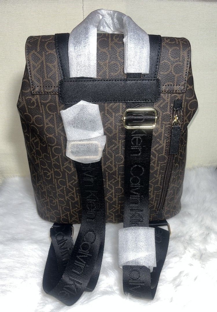 Calvin Klein Unisex Brown Monogram Backpack with Black Lining (Category: Backpacks) located in Imus. Submitted by maria_pilayo (Listing ID 1469971448, Image 2). Description: - Brand: Calvin Klein Unisex - 💯% Authentic - Color: Brown monogram with solid black accents - Size: Approx. 14" H x 11" W - Closure: Drawstring under front flap with polished gold hardware - Pockets: 2 front utility pockets with gold zippers - Straps: Adjustable back straps