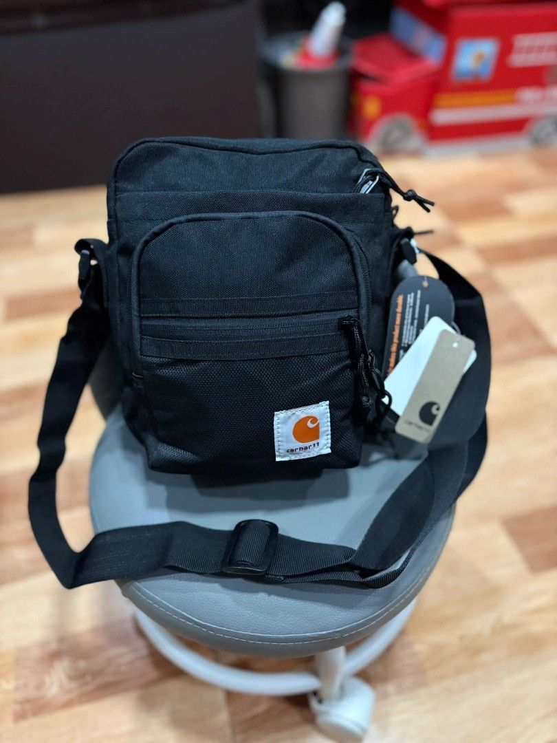 Carhartt Work In Progress Black Crossbody Bag (Category: Sling Bags) located in Tagum. Submitted by jenjen24867 (Listing ID 1470108760, Image 2). Description: Black Carhartt WIP crossbody bag. Durable fabric construction with multiple zip compartments and front pocket. Orange logo patch on the lower front. Adjustable shoulder strap attached. Tags still attached..