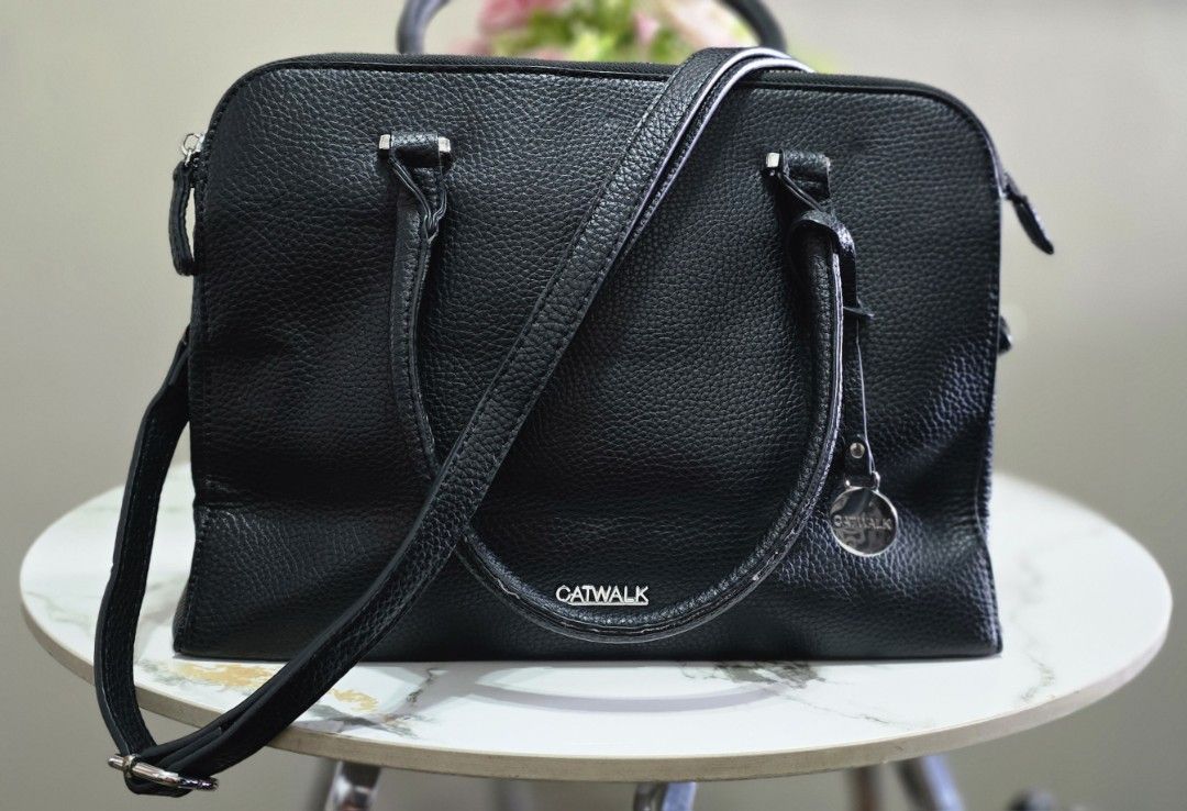 Catwalk Black Textured Handbag with Shoulder Strap (Category: Shoulder Bags) located in Manila. Submitted by ubasirene (Listing ID 1470083487, Image 1). Description: - Brand: Catwalk fromm sweden - Material: Black faux leather with textured pebble finish - Hardware: Sleek silver-tone zippers and rings - Carry Options: Dual top handles + adjustable, detachable shoulder strap - Closure: Secure top zip closure - Interior: Clean lining with multiple 