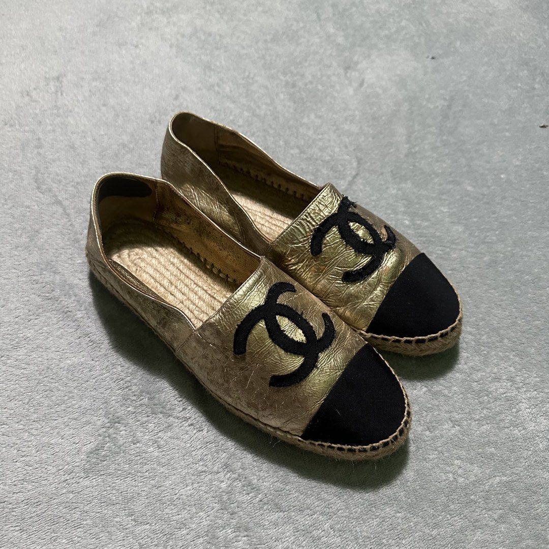 Chanel Gold Leather CC Espadrilles Flat Shoes (Category: Sneakers & Footwear) located in Villaverde. Submitted by bakatzy_secondhand_garments (Listing ID 1470093621, Image 2). Description: - Authentic Chanel espadrilles in eye-catching metallic gold leather - Contrasting black fabric toe cap with embroidered CC logo on the front - Classic jute braided midsole and easy slip-on design - Comfortable casual flats ideal for everyday styling - Conditio