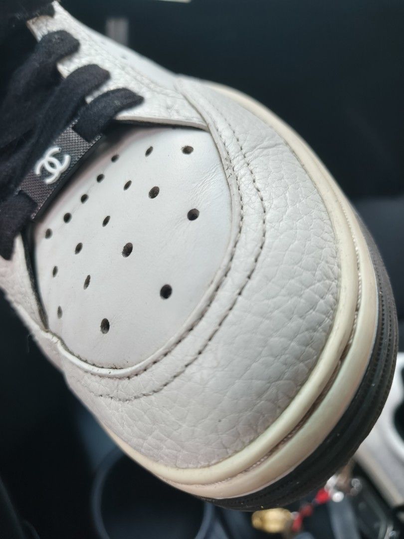 Chanel White and Black Leather Sneakers (Category: Sneakers & Footwear) located in Manila. Submitted by flicklex (Listing ID 1470060076, Image 3). Description: Chanel leather sneakers in white and black. Low-top design with perforated toe box and black laces. Branded tongue patch with the iconic CC logo. Metal hardware lace lock featuring the Chanel interlocking C. Textured leather panels and stitched details throughout. Pre-owned pair with visib
