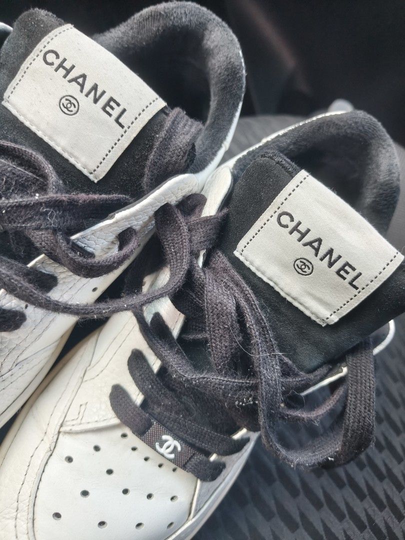 Chanel White and Black Leather Sneakers (Category: Sneakers & Footwear) located in Manila. Submitted by flicklex (Listing ID 1470060076, Image 1). Description: Chanel leather sneakers in white and black. Low-top design with perforated toe box and black laces. Branded tongue patch with the iconic CC logo. Metal hardware lace lock featuring the Chanel interlocking C. Textured leather panels and stitched details throughout. Pre-owned pair with visib