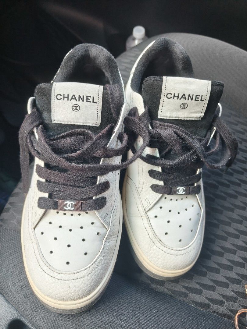 Chanel White and Black Leather Sneakers (Category: Sneakers & Footwear) located in Manila. Submitted by flicklex (Listing ID 1470060076, Image 2). Description: Chanel leather sneakers in white and black. Low-top design with perforated toe box and black laces. Branded tongue patch with the iconic CC logo. Metal hardware lace lock featuring the Chanel interlocking C. Textured leather panels and stitched details throughout. Pre-owned pair with visib