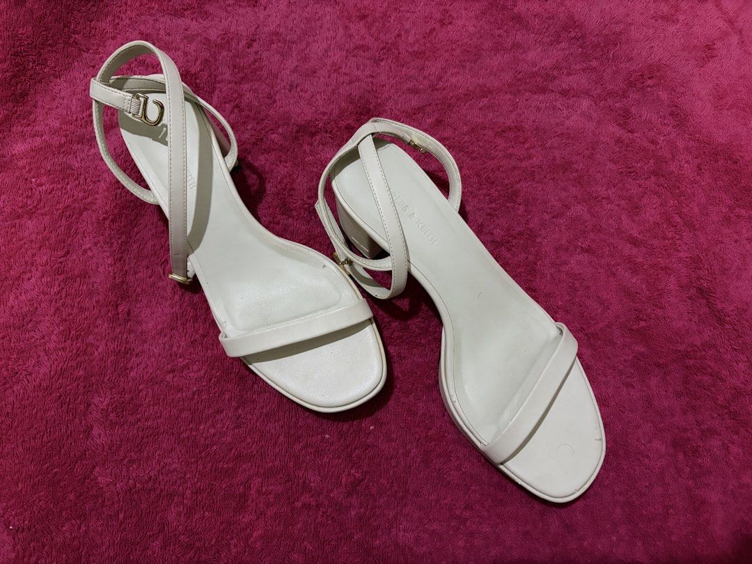Charles & Keith White Ankle Strap Heels (Category: Heels) located in Navotas City. Submitted by claragaddi (Listing ID 1470098345, Image 1). Description: - Brand: Charles & Keith - Style: Open toe heels with ankle strap, small platform, and block heel - Color: White - Size: 36 (stamped on inner sole) - Condition: Uppers are clean; soles show minor dirt from use.