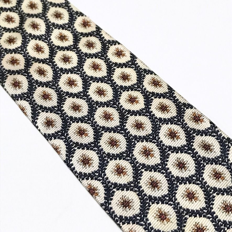 Christian Dior Repeating Floral Pattern Neck Tie (Category: Ties) located in Taguig. Submitted by retrogaze (Listing ID 1470080152, Image 3). Description: This 100% silk necktie by Christian Dior features an off-white cream base with a soft horizontal ribbed repp texture. The body is decorated with an ornate repeating geometric lattice pattern of dark navy blue leafy garlands framing starburst-like floral starburst motifs in warm rust-orange and 