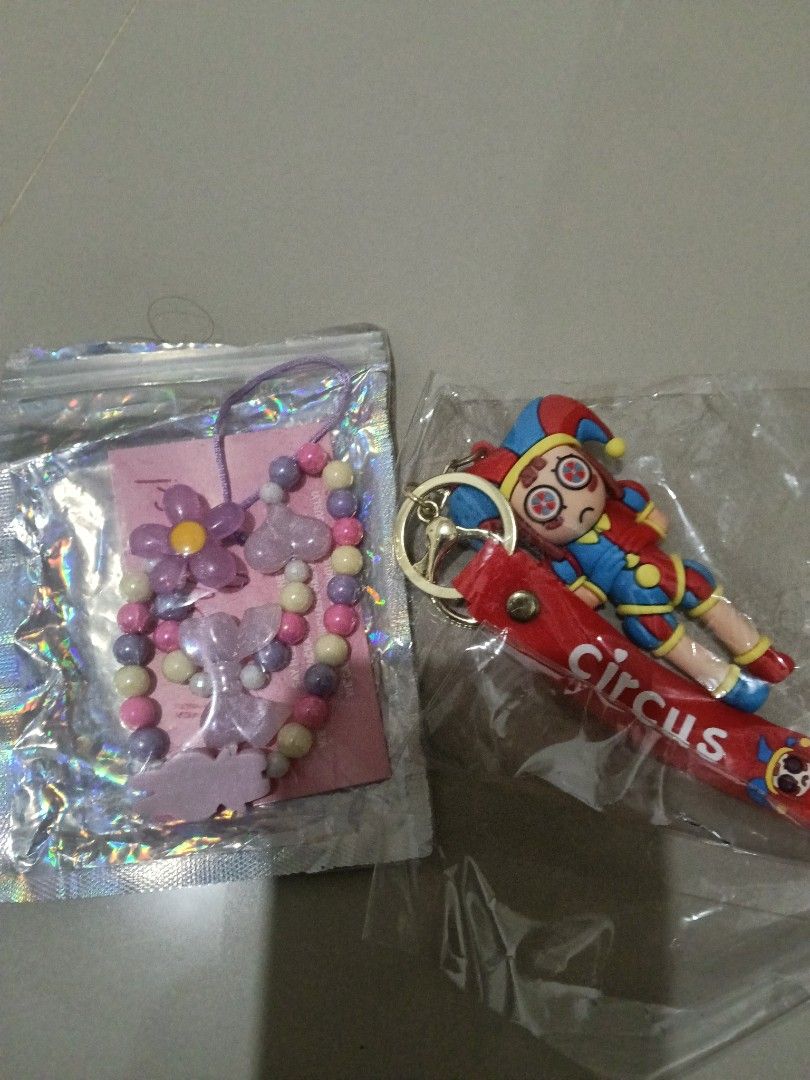 Circus Jester Keychain and Beaded Phone Charm Set (Category: Charms) located in Manila. Submitted by zenbear_6b2d8a (Listing ID 1470067318, Image 1). Description: - 2-in-1 Fun Accessory Bundle: Circus jester doll keychain with a red strap and a purple floral beaded phone strap. - Condition: Brand new, sealed in original plastic packaging. - Versatile Styling: Perfect for decorating your bags, keys, or phone. - Aesthetic: Features cute butterflies