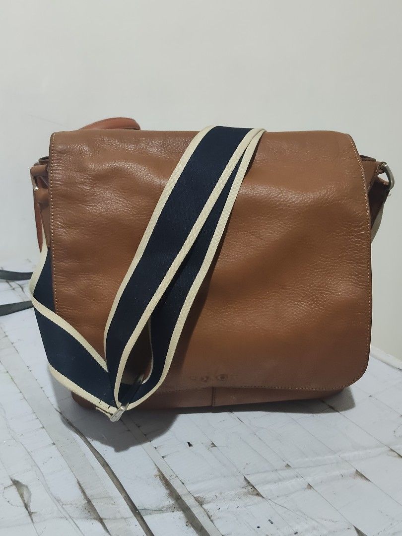 Coach Leather Messenger Bag Brown Blue Strap (Category: Sling Bags) located in Cebu City. Submitted by almzcorner (Listing ID 1469969879, Image 1). Description: - Authentic Coach brown leather messenger bag - Stylish navy and cream webbed strap - Flap closure with secure magnetic snap - Interior features a zipper pocket, slip pockets, and clean fabric lining - Signature leather story patch inside - Silver hardware stamped with the Coach logo - Co