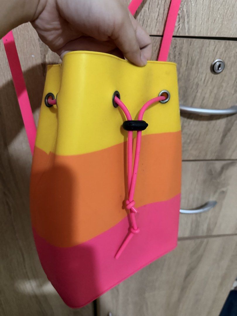 Colorful silicone bucket backpack pink orange yellow drawstring (Category: Backpacks) located in Manila. Submitted by tenshiii185 (Listing ID 1470056314, Image 3). Description: Bright tri-color silicone backpack in yellow, orange, and pink. Features a drawstring closure, black toggle, and adjustable pink straps. Fun, waterproof-texture everyday bag!.