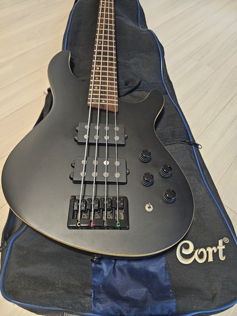 Cort C4H 4-Bass Guitar (Category: Musical Instruments) located in Manila. Submitted by minimalistbyheart (Listing ID 1469960227, Image 2). Description: - Model: Cort C4H Electric Bass Guitar - Finish: Sleek Matte Black - Pickups: Dual Humbucking pickups for a powerful tone - Fretboard: Dark wood - Origin: Made in Indonesia (Serial Number: 100312260) - Inclusions: Padded Cort gig bag, instrument cable, instruction DVD, and warranty card - Conditio