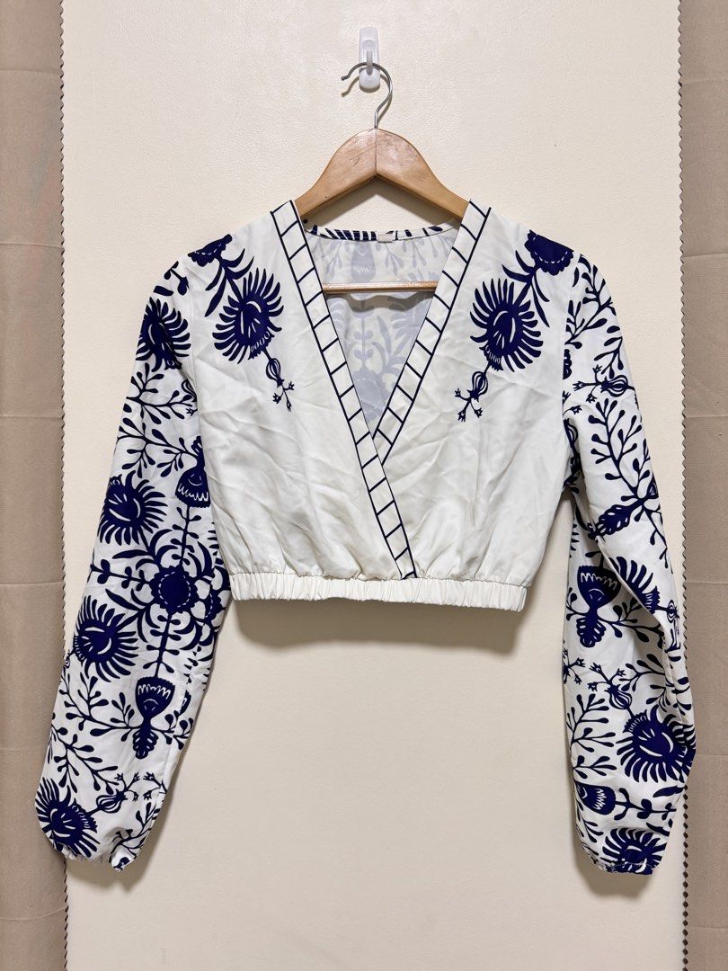Crop Top Long Sleeve (Category: Sleeveless) located in Manila. Submitted by seayouncey (Listing ID 1470057134, Image 1). Description: - Style: White crop top with dark blue floral print - Neckline: V-neck wrap front with grid stripe trim - Sleeves: Long sleeves with elastic cuffs - Fit: Comfortable elastic waistband, lightweight fabric - Back: Matching all-over floral pattern - Pairing: Great with high-waisted jeans or skirts.