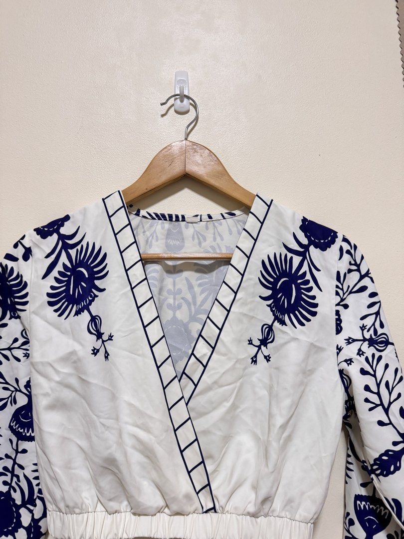 Crop Top Long Sleeve (Category: Sleeveless) located in Manila. Submitted by seayouncey (Listing ID 1470057134, Image 3). Description: - Style: White crop top with dark blue floral print - Neckline: V-neck wrap front with grid stripe trim - Sleeves: Long sleeves with elastic cuffs - Fit: Comfortable elastic waistband, lightweight fabric - Back: Matching all-over floral pattern - Pairing: Great with high-waisted jeans or skirts.