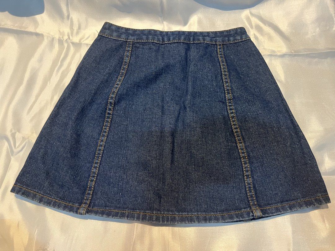 Dark wash denim skirt with front button closure (Category: Skirts) located in Manila. Submitted by ghengdhoze (Listing ID 1470061583, Image 2). Description: - Dark blue denim skirt - Classic A-line silhouette with structured panelling - Brass-toned metal button-front closure - Contrast yellow stitching & mid-rise waistband with belt loops - Clean finish hemline - Comes from a smoke-free home W-24-25in L-15in RFS - decluttering lalamove and grab r