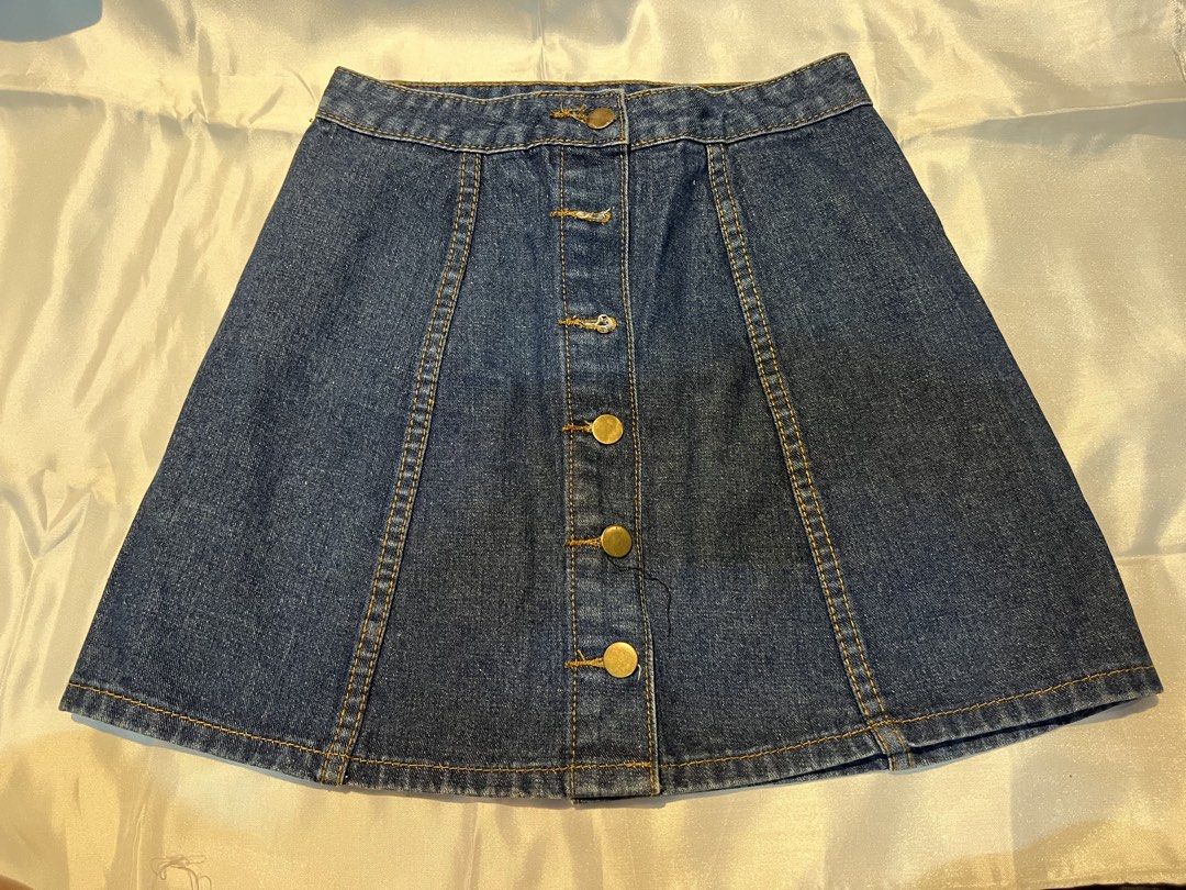 Dark wash denim skirt with front button closure (Category: Skirts) located in Manila. Submitted by ghengdhoze (Listing ID 1470061583, Image 1). Description: - Dark blue denim skirt - Classic A-line silhouette with structured panelling - Brass-toned metal button-front closure - Contrast yellow stitching & mid-rise waistband with belt loops - Clean finish hemline - Comes from a smoke-free home W-24-25in L-15in RFS - decluttering lalamove and grab r