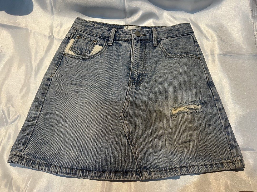 Denim Skirt Distressed Mini Raw Hem Size S (Category: Skirts) located in Manila. Submitted by ghengdhoze (Listing ID 1470066994, Image 1). Description: - Style: Blue denim mini skirt with a light fading wash - Design: Front distressed rip and chic asymmetric front seam - Details: Contrasting light pocket lining showing on the front right - Back: One regular pocket plus a unique open white lining pocket with a 'THINK BIG' tag - Features: Belt loop
