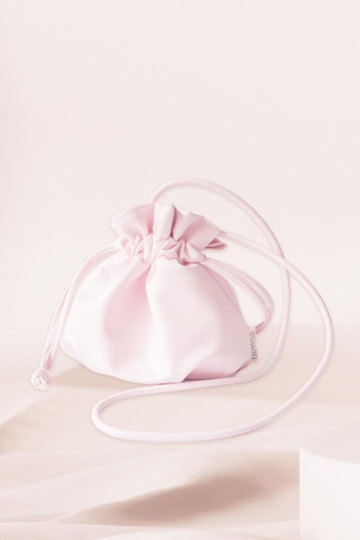Dewna Pink Drawstring Shoulder Bag (Category: Shoulder Bags) located in Makati City. Submitted by lexshie (Listing ID 1469972514, Image 1). Description: - Brand: Dewna - Color: Pastel pink - Material: Smooth faux leather - Closure: Drawstring top - Strap: Matching shoulder/crossbody strap (unused, still wrapped in original plastic) - Details: Small fabric brand tag on the side - Style: Minimalist everyday bag.