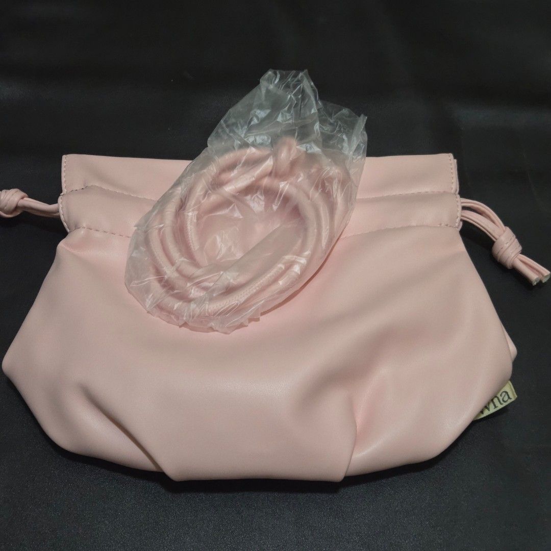 Dewna Pink Drawstring Shoulder Bag (Category: Shoulder Bags) located in Makati City. Submitted by lexshie (Listing ID 1469972514, Image 2). Description: - Brand: Dewna - Color: Pastel pink - Material: Smooth faux leather - Closure: Drawstring top - Strap: Matching shoulder/crossbody strap (unused, still wrapped in original plastic) - Details: Small fabric brand tag on the side - Style: Minimalist everyday bag.