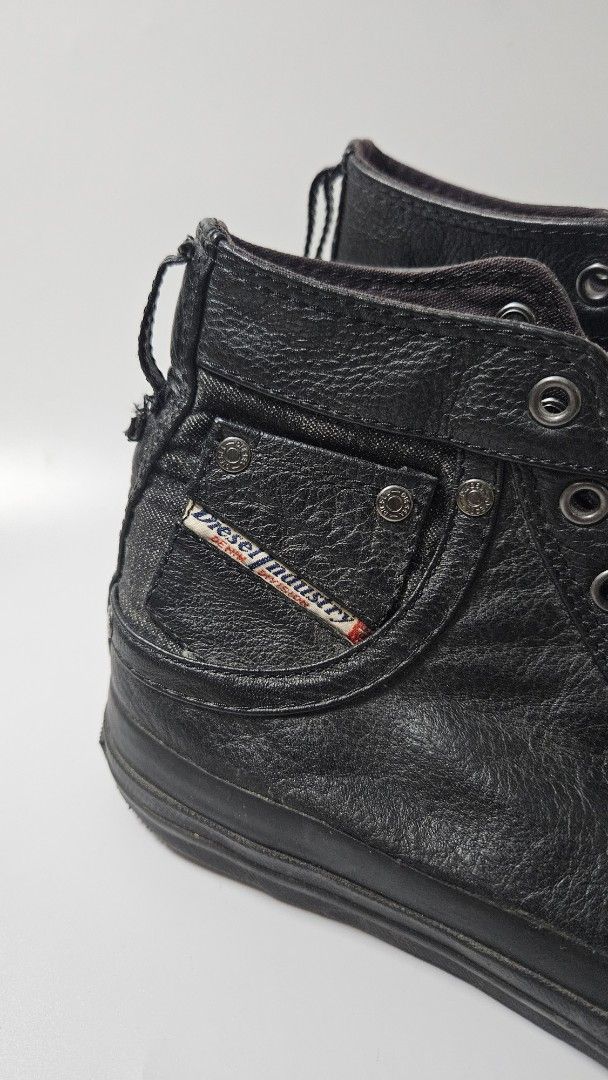 Diesel Black Leather High Top Sneakers (Category: Casual Shoes) located in Alfonso. Submitted by jbcamet (Listing ID 1470018625, Image 2). Description: - Brand: Diesel - Style: High-top sneakers - Material: Premium black leather - Details: Miniature denim side pocket with Diesel Industry branding - Features: Classic rubber toe cap, lace-up closure, and solid black soles - Insoles: Branded with the iconic 'Only The Brave' Mohawk graphic - Conditio