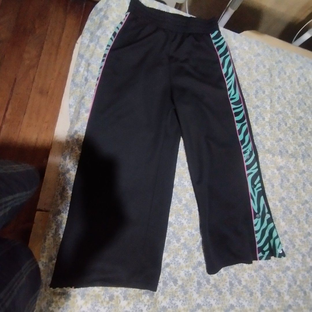 Divided Black Track Pants With Teal Zebra Side Strip (Category: Other Bottoms) located in Manila. Submitted by lene48 (Listing ID 1470026461, Image 2). Description: - Color/Design: Black with green and black zebra print side stripes outlined in pink - Closure: Elastic waistband for easy and comfortable wear - Features: Functional popper buttons down the sides of the legs - Fit: Relaxed wide-leg fit - Ideal for: Super comfy casual loungewear and t