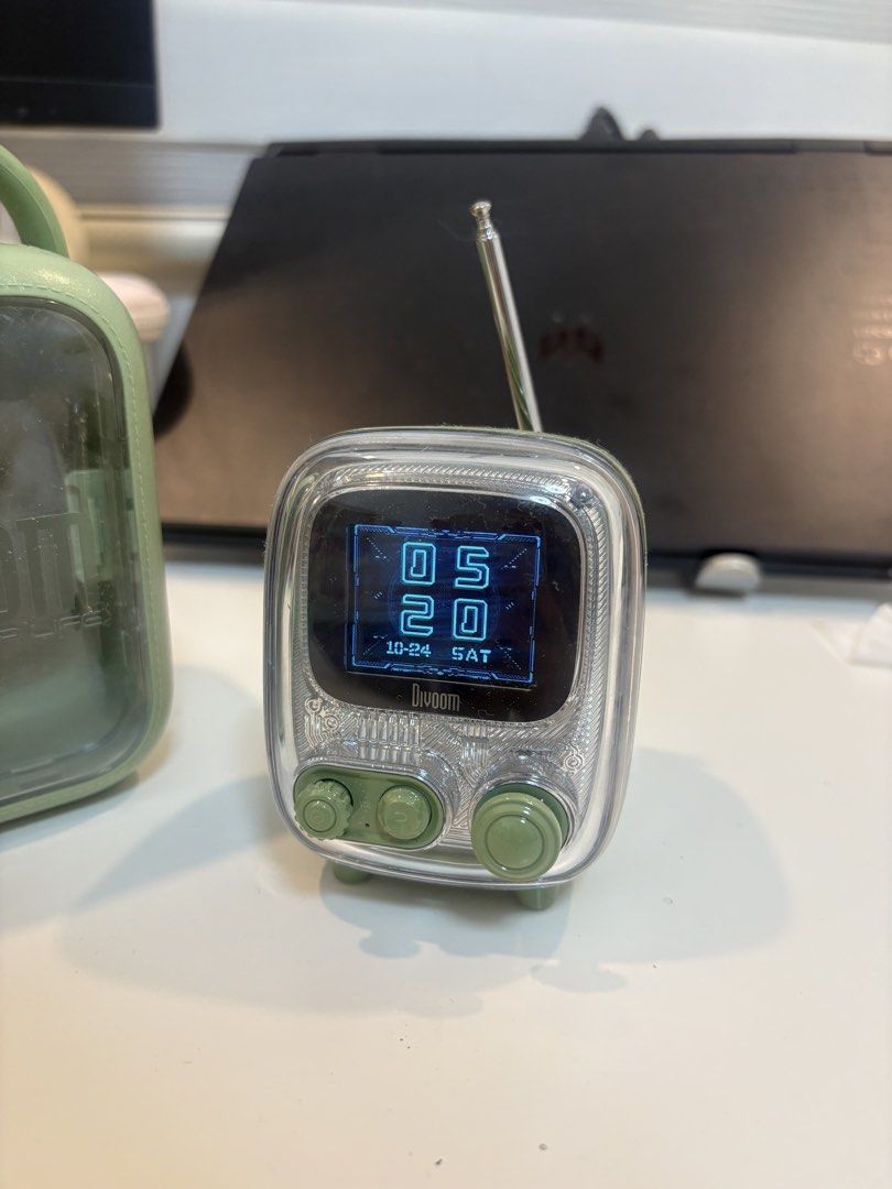 Divoom Tivoo 2 Pixel Art Speaker with Case (Category: Soundbars, Speakers & Amplifiers) located in Noveleta. Submitted by lalastore29 (Listing ID 1470040150, Image 2). Description: Divoom Tivoo 2 pixel art bluetooth speaker in green. Retro TV shape, transparent body, and retractable antenna on top. Comes with matching hard carrying case carrying the Divoom logo. Digital display on the front shows time and animations. Control knobs and buttons at 