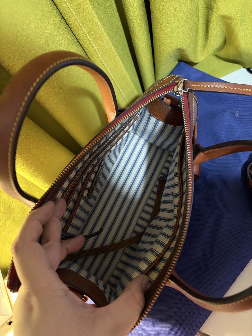 Dooney & Bourke Camden Satchel Handbag (Category: Cross-body Bags) located in Borongan. Submitted by charmspreloveddd (Listing ID 1470024815, Image 3). Description: - Brand: Dooney & Bourke - Material: Grey textured leather with brown leather trim - Hardware: Gold-tone with signature metallic duck logo - Closure: Top zip closure - Exterior: Front zippered pocket and structured side gussets - Interior: Blue and white striped fabric lining, slip po
