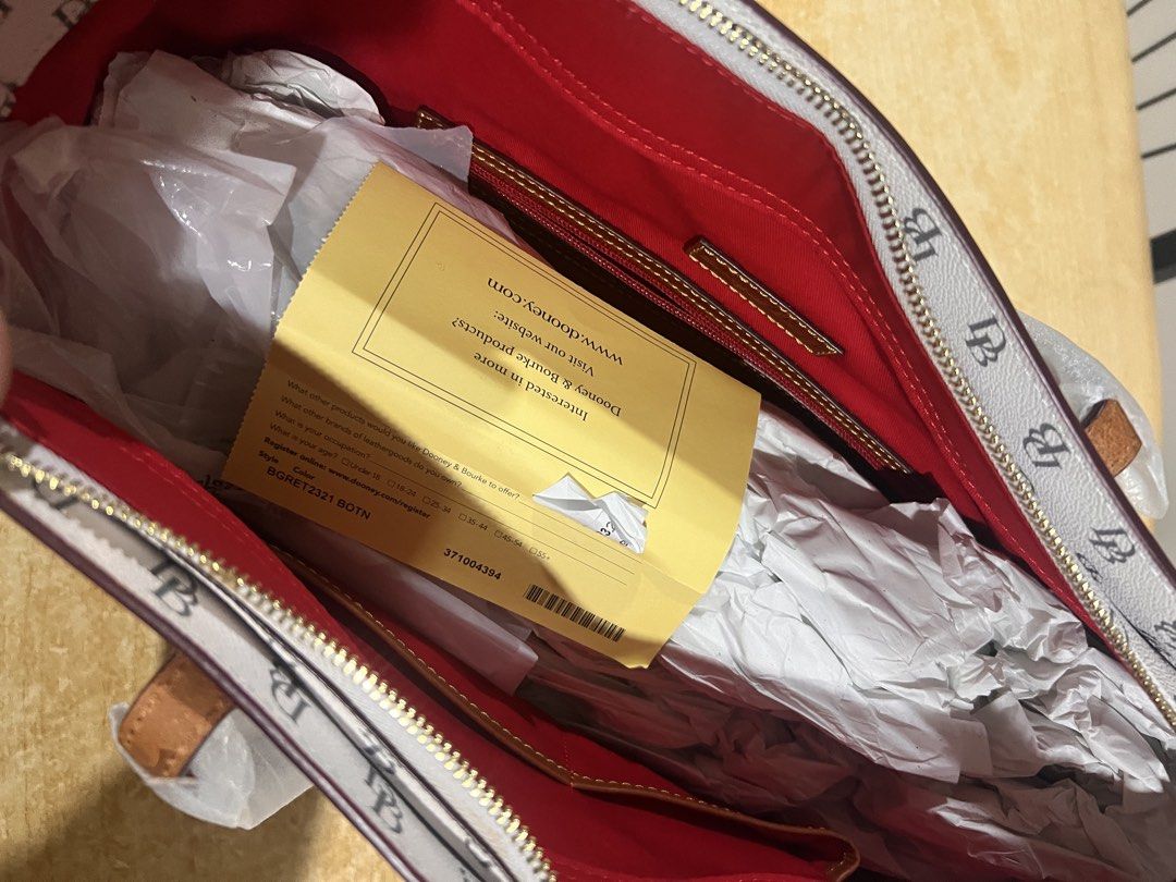 Dooney & Bourke DB Monogram Tote Bag (Category: Tote Bags) located in Davao. Submitted by sammmdizon7 (Listing ID 1470066200, Image 2). Description: - Authentic Dooney & Bourke tote bag - Iconic white & dark brown DB monogram print - Gold-tone hardware with front logo patch - Bright red interior lining with zip and slip pockets - Secure top zip closure - Brand new: handles still wrapped in original protective packaging - Includes original product