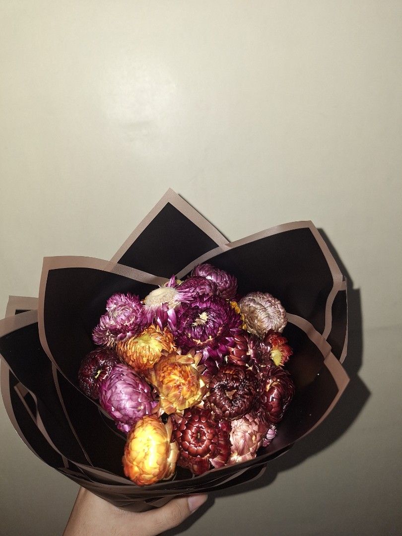 Dried everlasting flower bouquet (Category: Flowers & Bouquets) located in Manila. Submitted by noblegem04 (Listing ID 1470128216, Image 1). Description: - Stunning dried flower bouquet wrapped in dark brown paper with contrasting edges - Features a vibrant mix of purple, yellow, orange, and brownish-red everlasting strawflowers - Long-lasting preserved flowers that require zero maintenance - Perfect as a thoughtful gift idea or a chic room decor