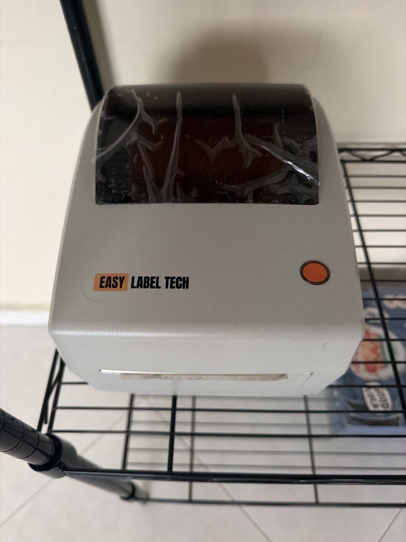 Easy Label Tech Printer (Category: Printers, Scanners & Copiers) located in Singapore. Submitted by loyzz (Listing ID 1470022907, Image 1). Description: - Brand: Easy Label Tech - Type: Thermal printer for shipping labels and tags - Color: Grey body with dark transparent top lid (original protective plastic film still on) USB type .