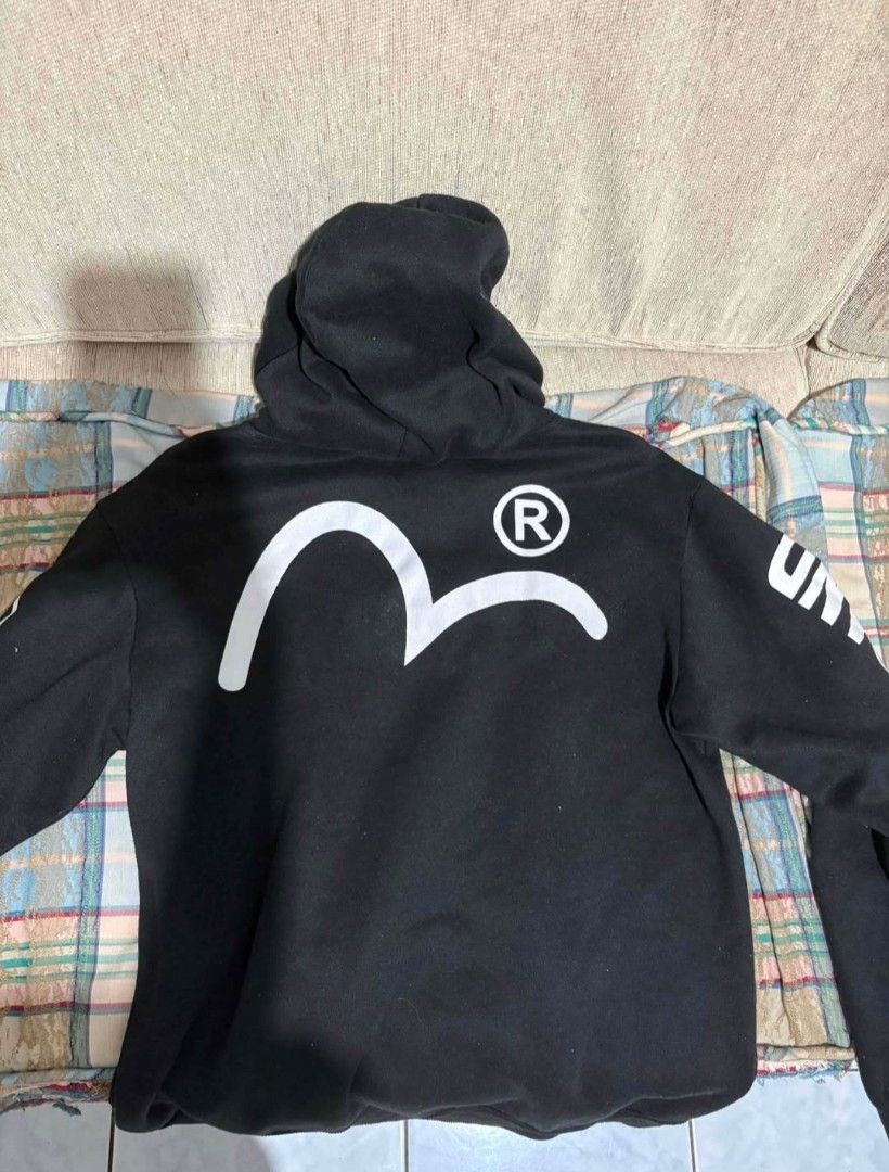 Evisu Black Hoodie (Category: Coats, Jackets and Outerwear) located in Manila. Submitted by jaysieseva620 (Listing ID 1470075773, Image 2). Description: - Brand: Evisu - Color: Black with contrasting white graphics - Material: Premium heavy cotton - Front: Text box logo and functional pouch pocket - Sleeves: 'ONE GOD BRAND' on the right, Japanese character and deity graphic on the left - Back: Large signature white gull logo with registered trade