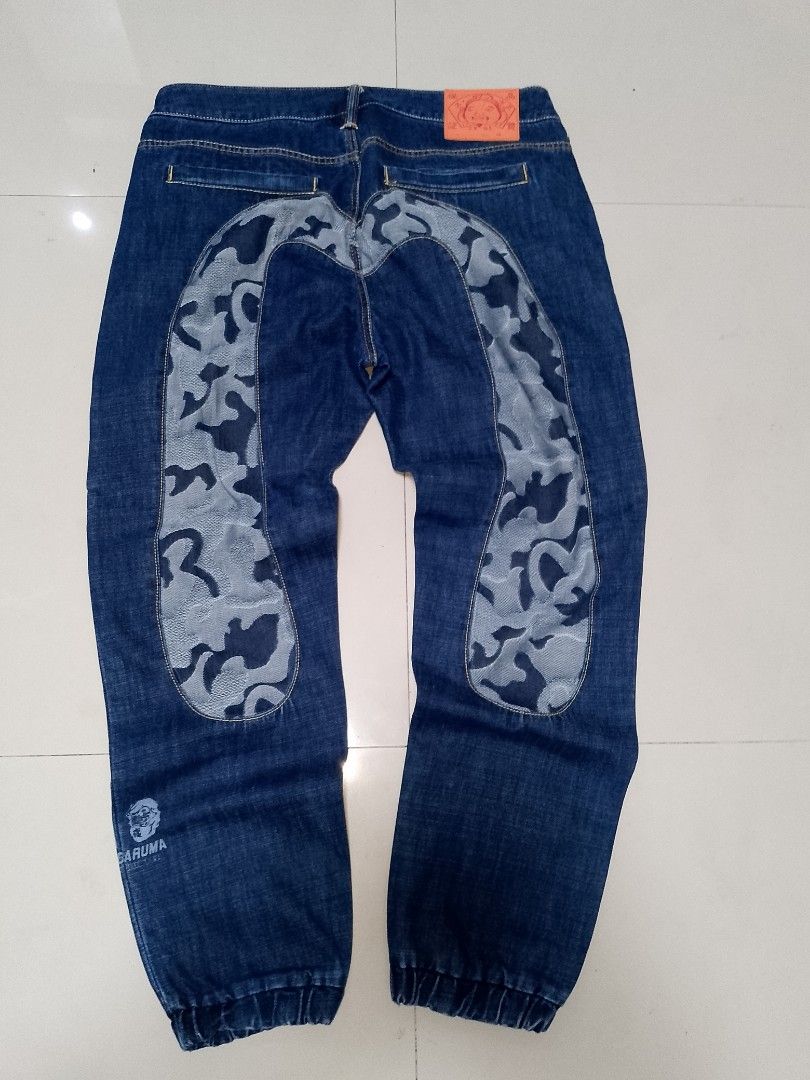 Evisu Daruma Camo Denim Joggers Size 36 (Category: Jeans) located in Manila. Submitted by mjthrifted_second (Listing ID 1469987803, Image 1). Description: - Brand: Evisu Daruma - Size: 36 (marked on leather patch) -Actual Size: 37/41 - Color/Wash: Clean blue denim - Unique Design: Camo print panels down the back and Daruma character graphics near the lower leg - Details: Elasticated ankle cuffs, button fly closure, and classic contrast stitching 