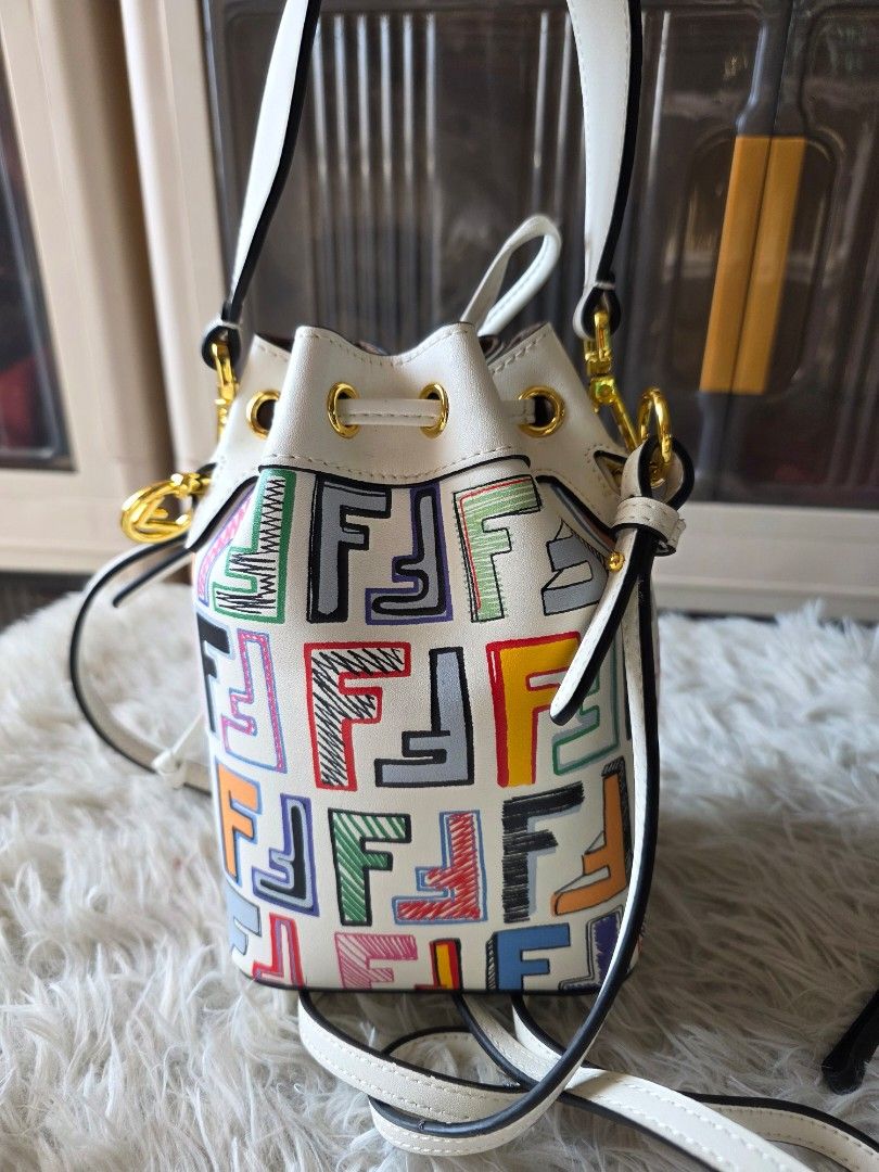 Fendi Mon Trésor Bucket Bag Graffiti White Multi (Category: Cross-body Bags) located in Lemery. Submitted by venus23 (Listing ID 1470140631, Image 2). Description: - Brand: Fendi Mon Trésor Bucket Bag - Material: White leather with colorful sketched logo prints - Hardware & Lining: Gold-tone hardware with brown suede interior - Closure: Secure drawstring closure - Straps: Includes detachable top handle and adjustable/detachable shoulder strap - O