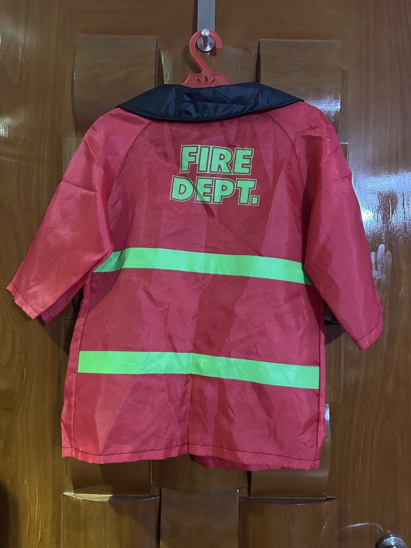 Fire Dept Costume Jacket (Category: Babies & Kids Fashion) located in Muntinlupa City. Submitted by belica (Listing ID 1470086473, Image 2). Description: - Color: Red with black collar/pockets and neon green safety stripes - Back Design: Large 'FIRE DEPT.' printed lettering - Features: Front toggle closures and two patch pockets with clear lower sections - Fit: Standard regular fit - Condition/Use: Fun dress-up or costume piece.